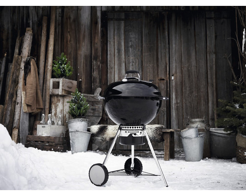 Guľový gril v snehu pred drevenou chatou