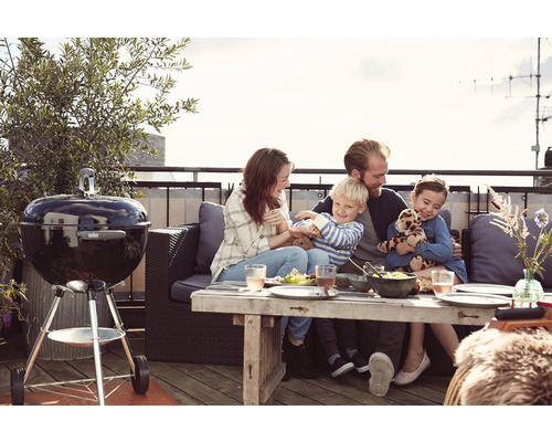 Rodina si užíva grilovanie s guľovým grilom na strešnej terase.