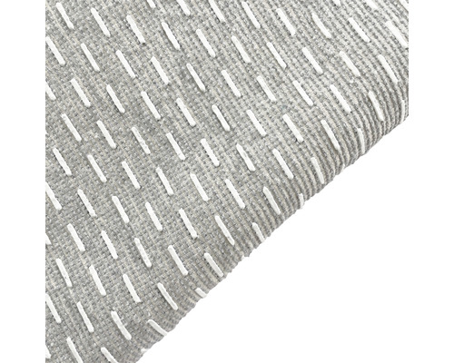Detail šedého koberca s bielym ozdobným prešívaním