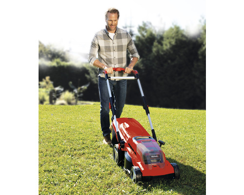 Muž obsluhuje kosačku na trávu na lúke.