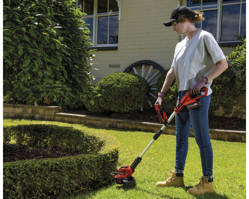 Žena používa akumulátorový vyžínač na záhrade.