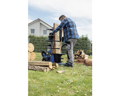 Muž štiepa drevo štiepačkou na drevo v záhrade.