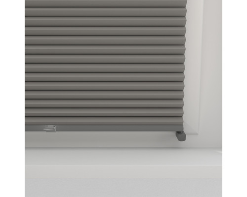 Detail šedej plisovanej žalúzie do okna na reguláciu svetla a dekoráciu