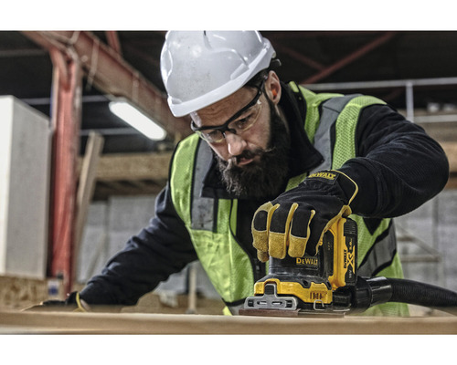 Robotník používa vibračnú brúsku Dewalt na brúsenie kusu dreva