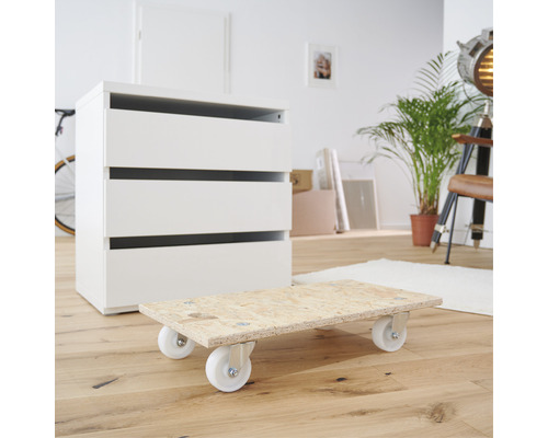 Drevený vozík na nábytok s bielymi kolieskami pred bielou komodou