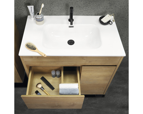 Skrinka pod umývadlo z dreva s otvorenou zásuvkou a rôznymi kúpeľňovými potrebami na povrchu