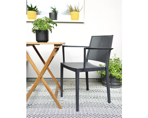 Záhradný nábytok so stoličkou s podrúčkami, dreveným stolom a kobercom na terase