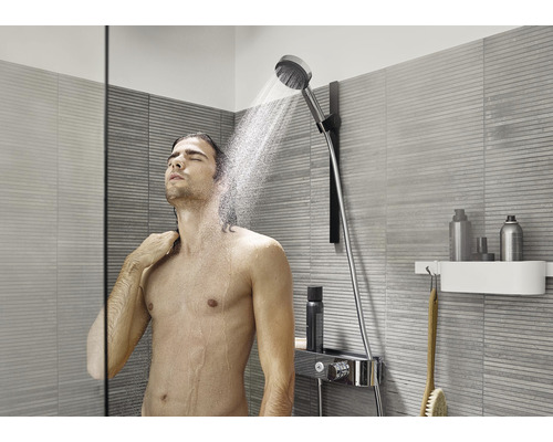 Muž pod ručnou sprchou v modernej kúpeľni