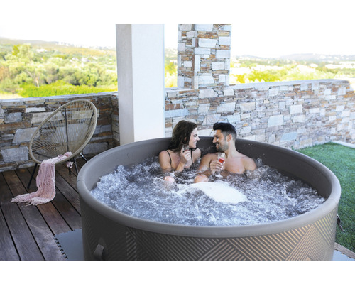 Nafukovacia vírivka s dvoma ľuďmi na terase s kamennými prvkami a stoličkou