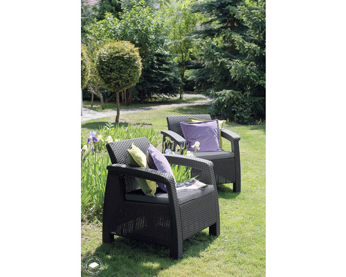 Dve záhradné ratanové kreslá s vankúšmi v záhrade.