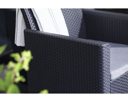 Detail čierneho ratanového kresla s vankúšom a uterákom