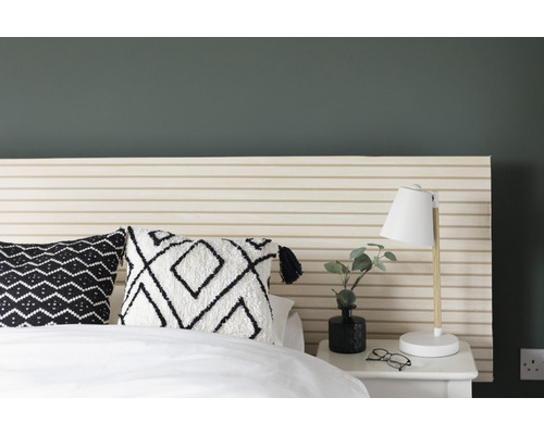 Spálňa s posteľou, vzorované vankúše a nočná lampa