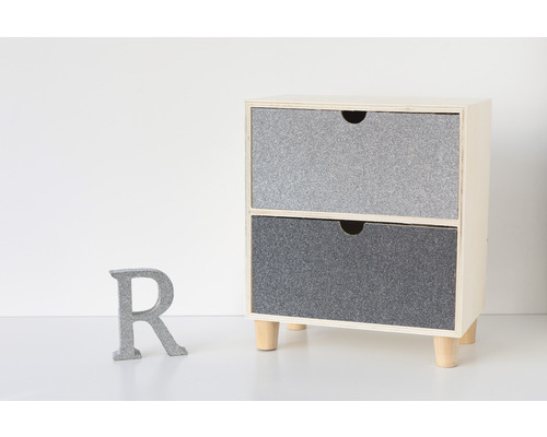 Malá skrinka s dvoma zásuvkami a drevenými nohami vedľa sivého písmena R.