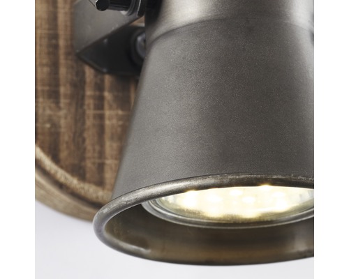 Detail nástennej lampy s drevenou základňou a kovovou hlavou