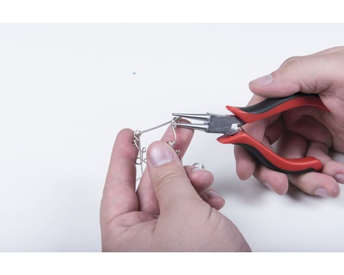 Osoba ohýba drôt okrúhlymi kliešťami.