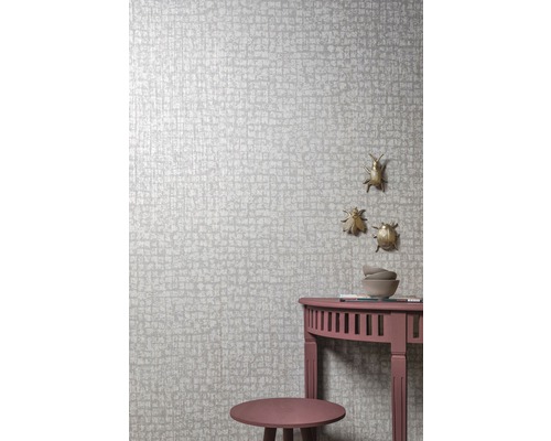 Detail steny s tapetou so vzorom, malý stolík a ozdobné chrobáky