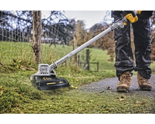Pohľad zhora na osobu, ktorá strihá trávnik pomocou akumulátorového vyžínača