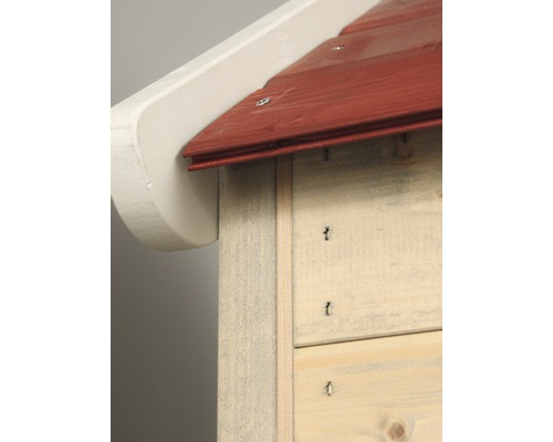 Detailný pohľad na hmyzí hotel s červenou strechou a bielym presahom strechy