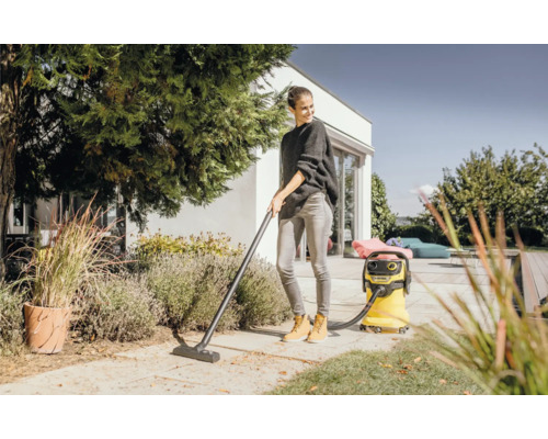 Žena používa žltý viacúčelový vysávač Kärcher v záhrade na odstraňovanie lístia