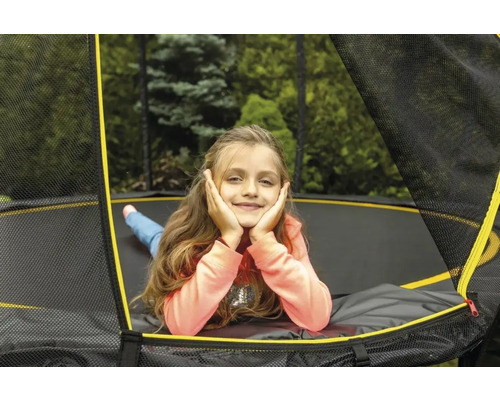 Dievča relaxuje na záhradnej trampolíne s bezpečnostnou sieťou