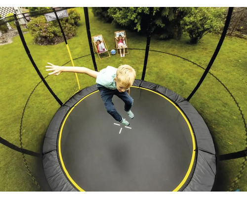 Chlapec skáče na okrúhlej záhradnej trampolíne so sieťou