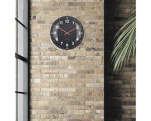 Čierne nástenné hodiny s červenou ručičkou na tehlovej stene