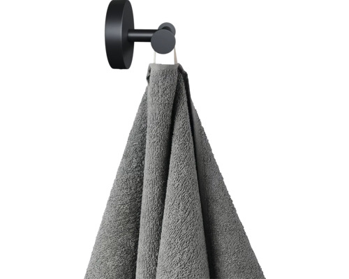 Sivý uterák visí na čiernom háčiku na uteráky
