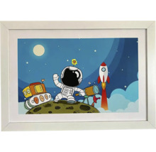 Zarámovaný obrázok s astronautom, lunárnym vozidlom a raketou na mesačnej krajine