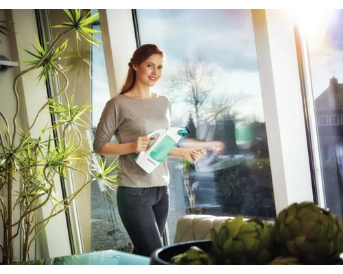 Žena čistí okná pomocou vysávača okien v obývacej izbe