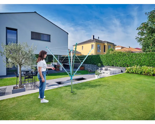 Sušiak na bielizeň v záhrade so ženou a domom v pozadí