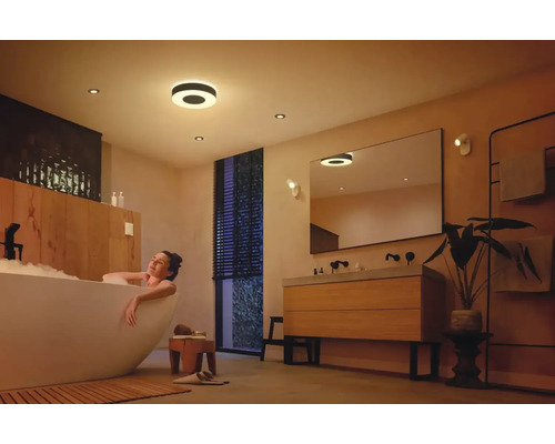 Svetlá kúpeľňa so stropnými svietidlami a ženou vo vani