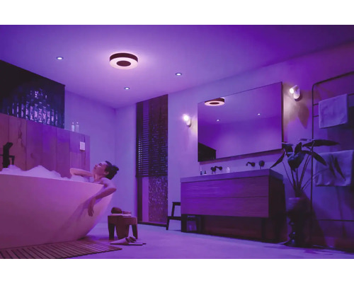 Žena relaxuje vo vani pod stropnými a vstavanými svetlami v kúpeľni