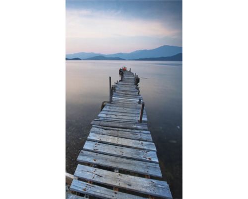 Drevené mólo vedie do pokojnej vody s horami v pozadí.