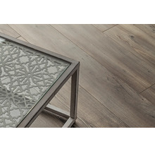 Detailný pohľad na stôl so sklenenou doskou a dekoratívnym vzorom, vedľa drevená podlaha.