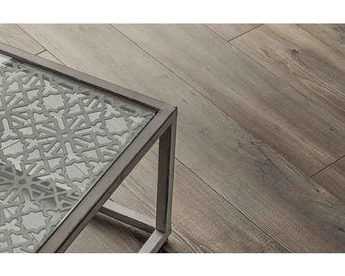 Detailný pohľad na stôl so sklenenou doskou a dekoratívnym vzorom, vedľa drevená podlaha.