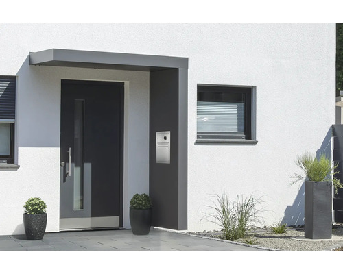 Vchodová strieška Gutta BS Plus 160 RAL 7016 antracit 200x90 cm, pravý bočný diel vrátane poštovej schránky, integrovanej kamery a domáceho telefónu, nerezový odtok vody v bočnom diele Vonkajší pohľad na dom so vstupnými dverami, poštovou schránkou a oknami