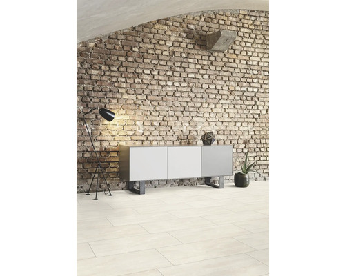 Obývacia izba s tehlovou stenou, komodou, stojacou lampou a dlažbou