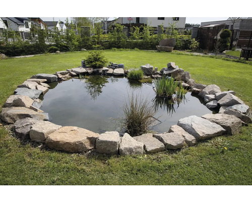Záhradné jazierko s kamenným okrajom na trávniku.