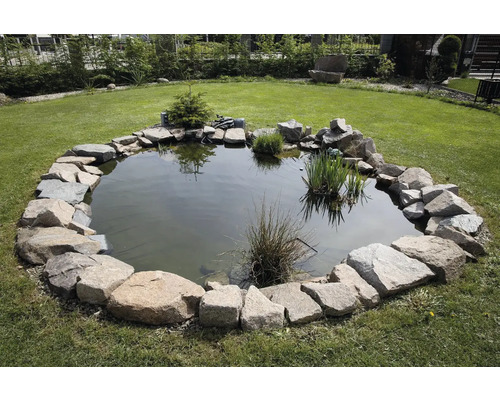 Záhradné jazierko s kamenným obrubníkom a rastlinami na trávniku