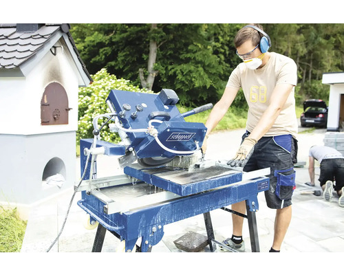 Muž obsluhuje pílu na kameň pre stavebné práce vonku.