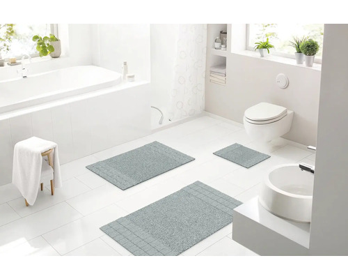Svetlá kúpeľňa s vaňou, umývadlom, toaletou a tromi sivými kúpeľňovými kobercami