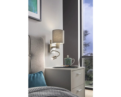 Nástenná lampa s lampičkou na čítanie nad nočným stolíkom v spálni.